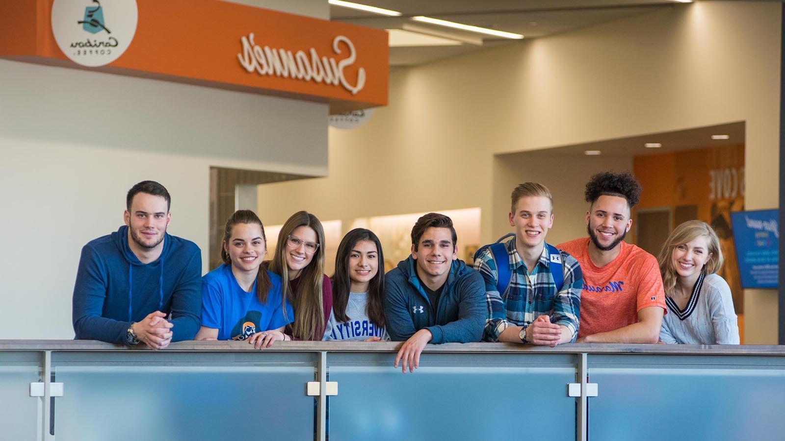 Eight University of Mary students smiling and overlooking balcony in the Lumen Vitae University Center